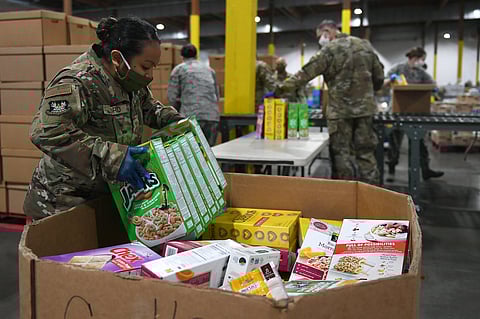 Senior Airman Kelly Ford, 194th Logistics Readiness Squadron, packs food boxes at the Food Lifeline COVID-19 Response warehouse on April 23, 2020, in Seattle, Washington. (Photo: Master Sgt. Tim Chacon, under a Creative Commons, CC BY 2.0 license.)