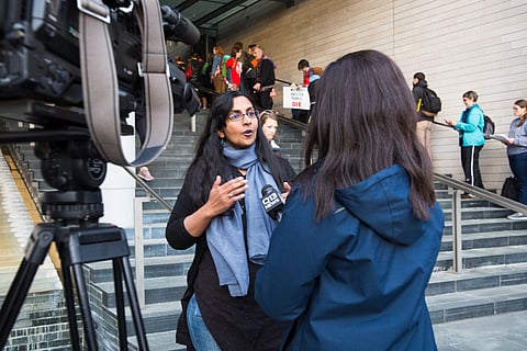 Councilmember Kshama Sawant speaks to a television news reporter on the steps of Seattle City Hall in 2017. (Photo courtesy of Real Change.)