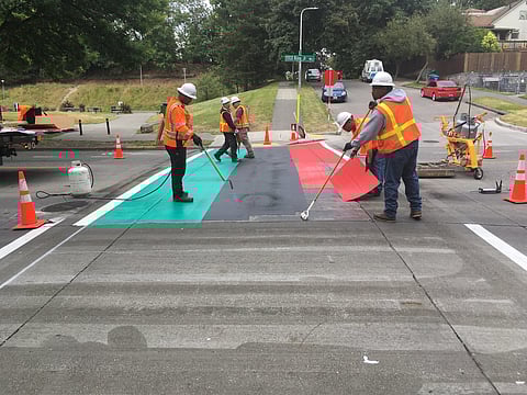 Seattle Department of Transportation workers installing a new red, black, and green crosswalk at Martin Luther King Jr. Way and East Alder Street, June 20, 2016. Photo is attributed to SDOT Photos (under a Creative Commons, CC BY-NC 2.0 license.)