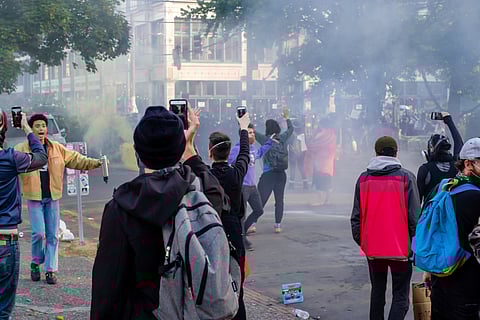 Seattle police disperse demonstrators with flash bangs and pepper spray near an SPD precinct. June 6, 2020. Photo via Mauro Pedro da Silva/Shutterstock.com