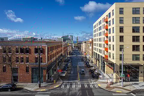 At Uncle Bob's Place (right, light-colored brick building), an affordable housing complex developed by InterIm CDA and named in honor of the late activist Bob Santos, a row of red balconies adorned with community-created designs is prominently displayed. (Photo: Rick Wong)