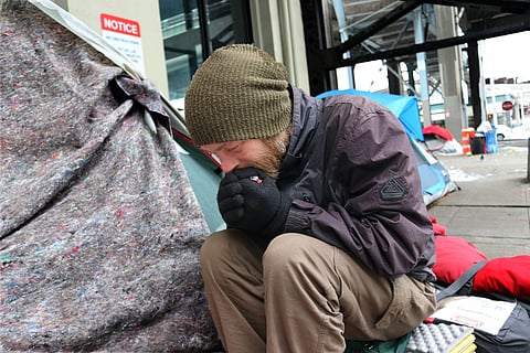 Sean Struble tries to warm his hands while sitting outside a friend's tent on Marion Street in downtown Seattle, February 2019. (Photo: Jon Williams)
