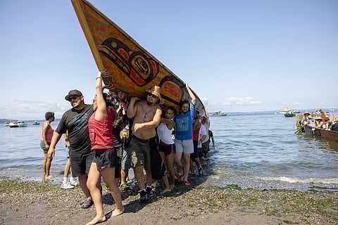 A canoe family carries their canoe out of the water and onto land at Alki Beach. "We care for the canoes like they are one of us," said John Daniels Jr., Muckleshoot Tribal Council treasurer. (Photo: Alex Garland)