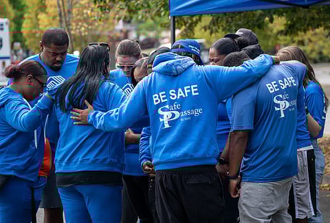 Members of the Safe Passage team huddle for prayer before starting Thursday's press conference at Rainier Beach Safeway parking lot. (Photo: Susan Fried)