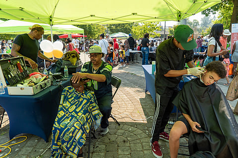 Frank Taylor (center) from Frank's Barbershop and a dozen more barbers and beauticians offered free haircuts to kids and adults during the 20th Annual Back2School Bash on Aug. 26 at Rainier Beach Community Center. (Photo: Susan Fried)