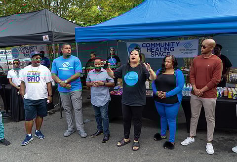SE Network SafetyNet Executive Director Marty Jackson (center) emphasizes the need for the return of Safe Passage and Community Healing Space to the Rainier Beach Safeway parking lot. On her right is Ricole Jones, and far right is King County Councilmember Girmay Zahilay. Safe Passage Director D'Mario Mallory is second from the left. (Photo: Susan Fried)
