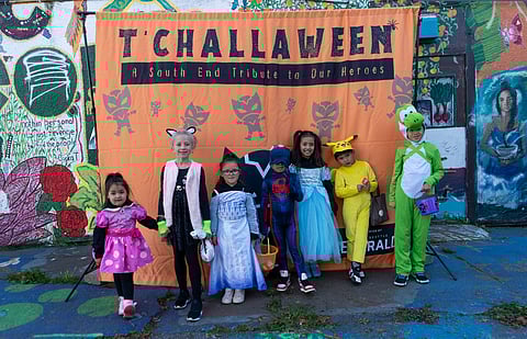 A group of costumed youth pose for a photo in front of the T'Challaween banner in Beacon Hill's Feed the People Plaza. (Photo: Susan Fried)