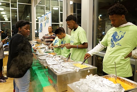 Youth serve and receive food at the community dinner for Turkey Bowl Week in 2018. (Photo: Susan Fried)