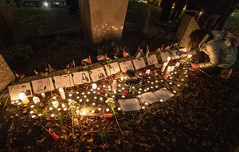 A person lights a candle at a shrine set up for the more than 60 journalists killed in the latest war between Israel and Hamas. Dozens of local journalists and community members gathered at Jose Rizal Park on Sunday, Dec. 10, to honor the lives of the journalists killed in the conflict. (Photo: Susan Fried)