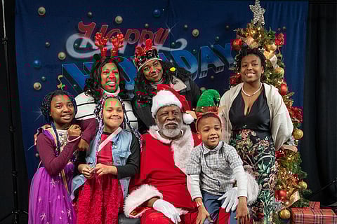 First-grade teacher Taryn and her family pose with Santa on Dec. 17 at the annual Royal Esquire Club & Sundiata African American Cultural Association Toy Giveaway. (Photo: Susan Fried)