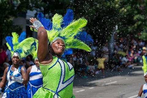 A member of the Washington Diamonds Drill Team throws some glitter into the air during a performance by the team for the crowd along the Africatown Heritage Parade route. (Photo: Susan Fried)