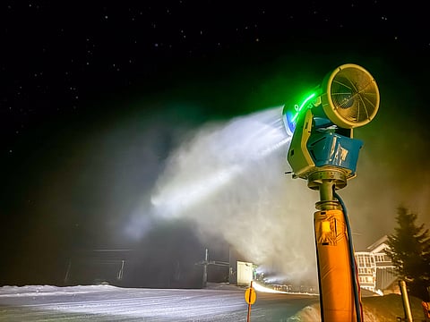 A snowmaker at work during the night at a ski resort.