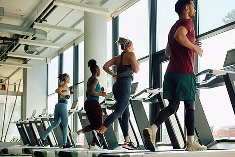 Four people running on treadmills at the gym.