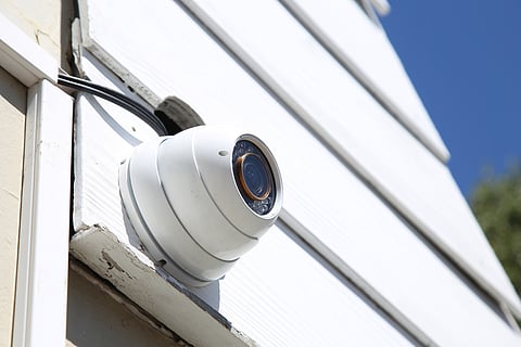 A security camera mounted to the side of a white building.