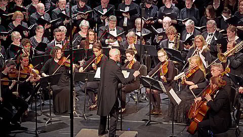 A conductor standing in front of a full orchestra.