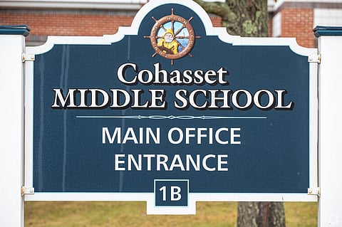 Image is an upclose view of a blue sign with white lettering that says "Cohasset Middle School Main Entrance" A school committee meeting discussing updates to the middle school curriculum on cyberbullying and student wellness.