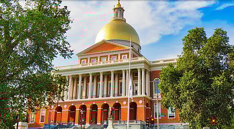 exterior shot of the Massachusetts state house with red bricks, white columns, and a gold dome.