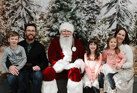 A family poses in front of a winter scene for a Christmas card.