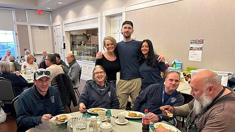 A group of elders sits around a table with a fish dinner. Cohasset Elder Affairs hosts lunch for seniors featuring donated seafood from local restaurants and prepared by community volunteers.