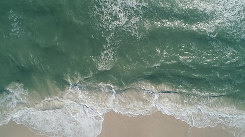 Gray green water and white caps on the beach