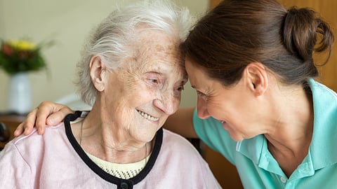 a younger woman and older woman put their heads together in a touching gesture