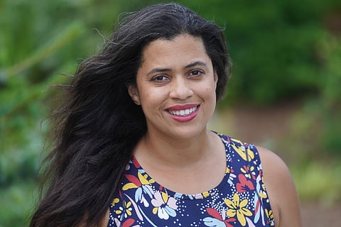 Woman with dark hair wearing bright pink lipstick and a floral tank top