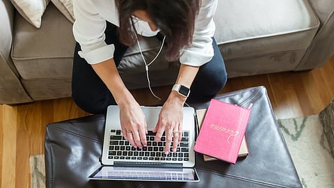 A woman sitting on a couch leaning over her laptop typing. Three often-overlooked factors—energy, props, and planning—transform brand photoshoots into powerful, authentic imagery.