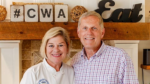 a man and woman wearing a chef's coat pose and smile