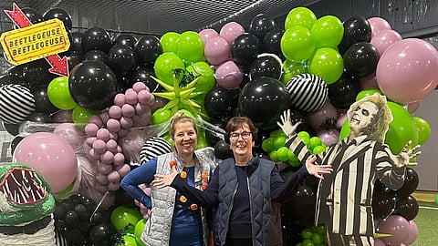 two women stand in front of a halloween balloon display
