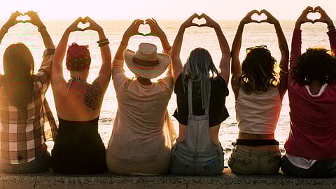a diverse group of women hold up their hands in the shape of a heart
