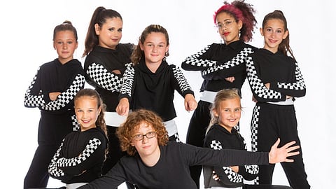 Dancers pose during a photoshoot, capturing movement and confidence in a warm, welcoming studio.