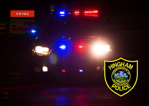 A police car with its lights on and a Hingham Police Patch
