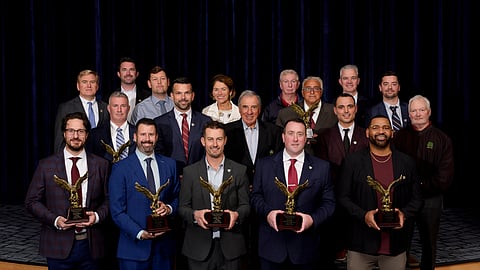 a group of men stand holding eagle trophies