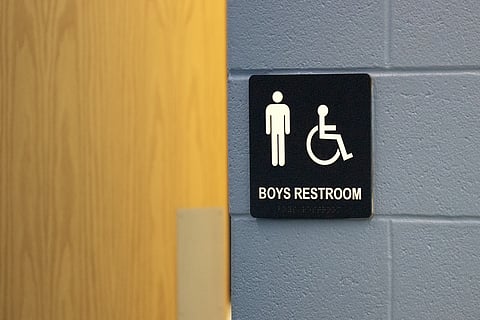 A boys bathroom sign on a concrete block wall.
