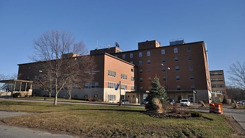 The outside of Tewksbury Hospital, a large brown building.