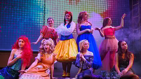 a group of teenage girls dressed up as princesses for a musical production