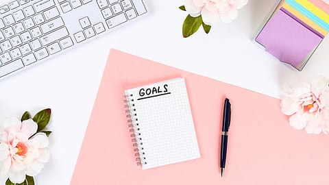 A desk with a notepad that says goals on it