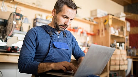 A male small business owner reading information on his laptop.