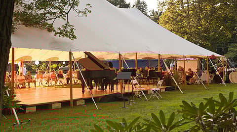outdoor tent filled with musicians and concert goers at an outdoor music festival