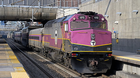 The purple commuter rail train stopped at a station.