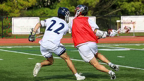 Student lacrosse athletes practicing spring sports drills on a field in Hanover and Hingham as experts discuss injury prevention strategies.