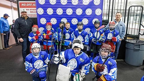kids in hockey gear pose for a photo