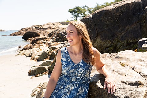 a woman smiles while wearing a blue dress on the beach
