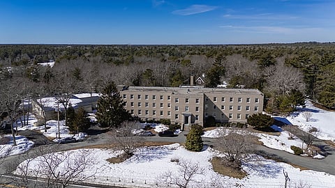 a large brown building with trees and snow around it