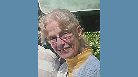 picture of older white woman wearing glasses with blonde hair and a yellow turtleneck