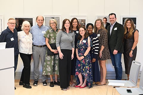 a group of people pose at the norwell public library in front of a white wall