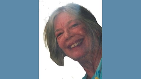 An older white woman wearing a blue shirt with grey hair
