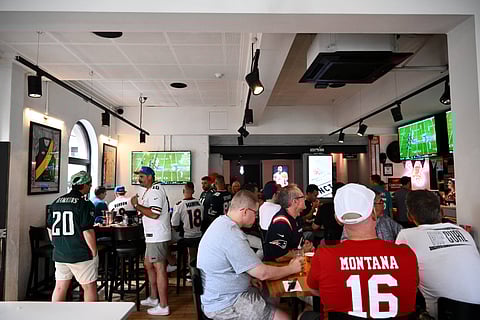 Fans watching Super Bowl LX between Seattle Seahawks and New England Patriots at a bar
