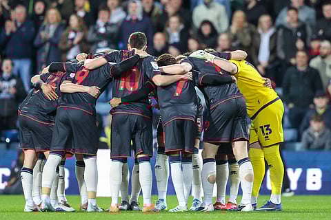 Millwall FC players in a team huddle