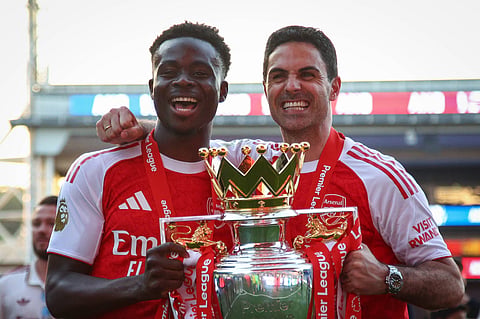 Bukayo Saka and Mikel Arteta pose with the Premier League trophy